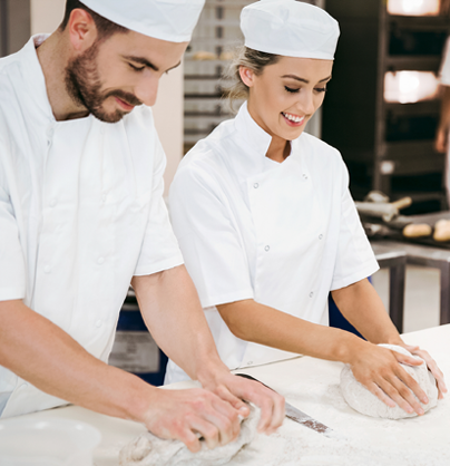 Symbolbild für Berufsbildung: Zwei Bäckerlernende formen ein Brotteig. 